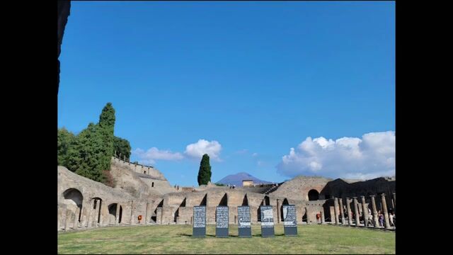 Ancient Roman ruins in Pompeii featuring tall stone columns, preserved frescoes, mosaic floors, and distant volcano.